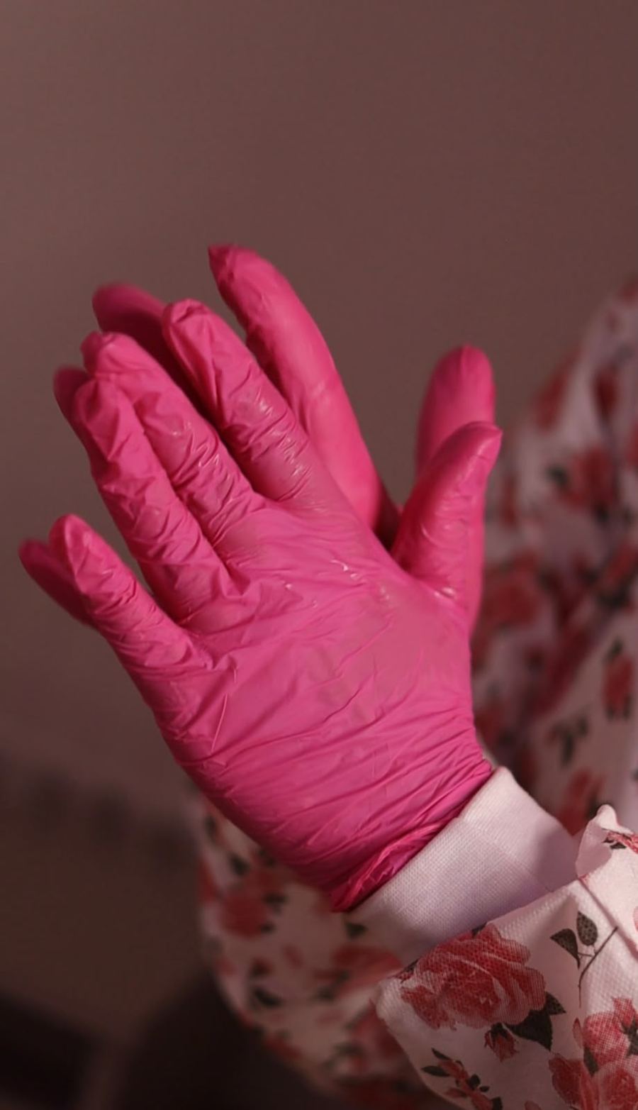 Mão com luva descartável rosa